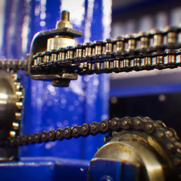 Close up of a chain drive and sprocket on a blue plate loaded machine