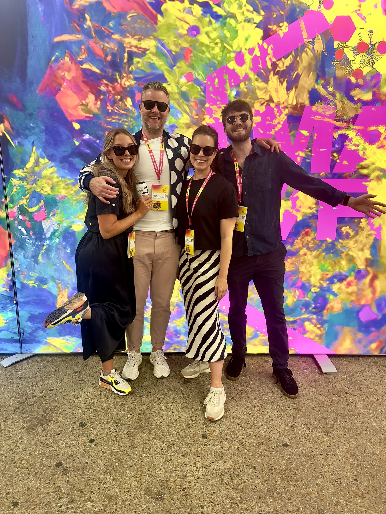 Luke Gray with the Create Inc team posing in front of a bright paint-splash backdrop at MAD//Fest