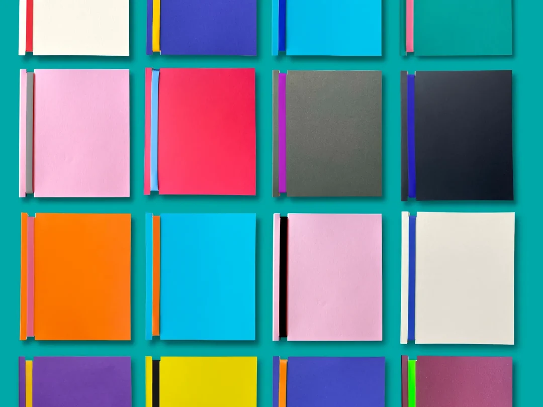 Dizzy Ink Book for Life notebooks laid out in a grid of colourways on teal