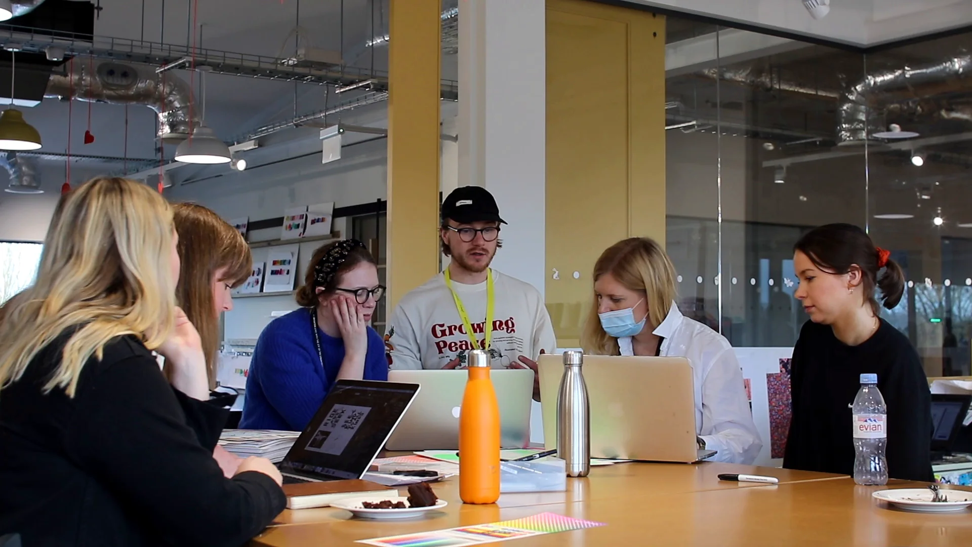 The Joules team designing at a long table with laptops and sketchbooks in the studio