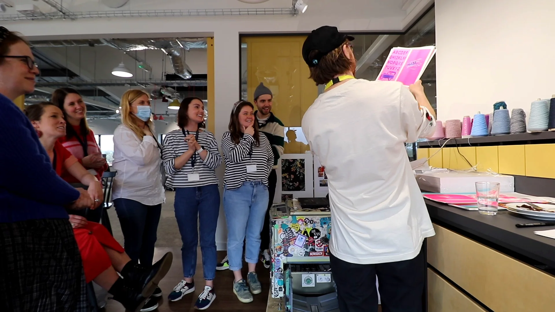 A Dizzy Ink host holds up a fresh pink print as the Joules team gathers round the risograph and cheers