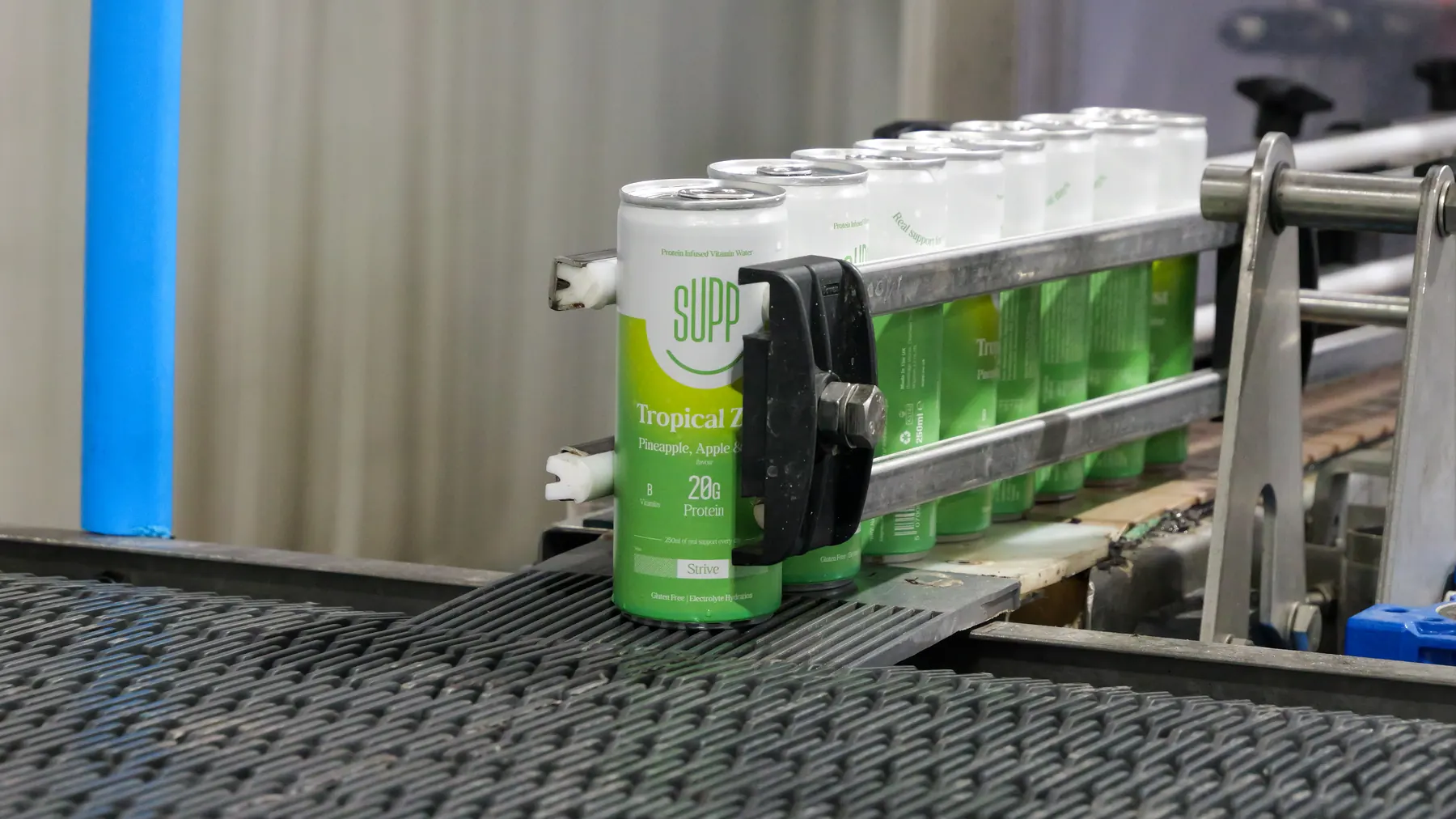 Supp protein water can in focus at the front of a line of cans on the production conveyor