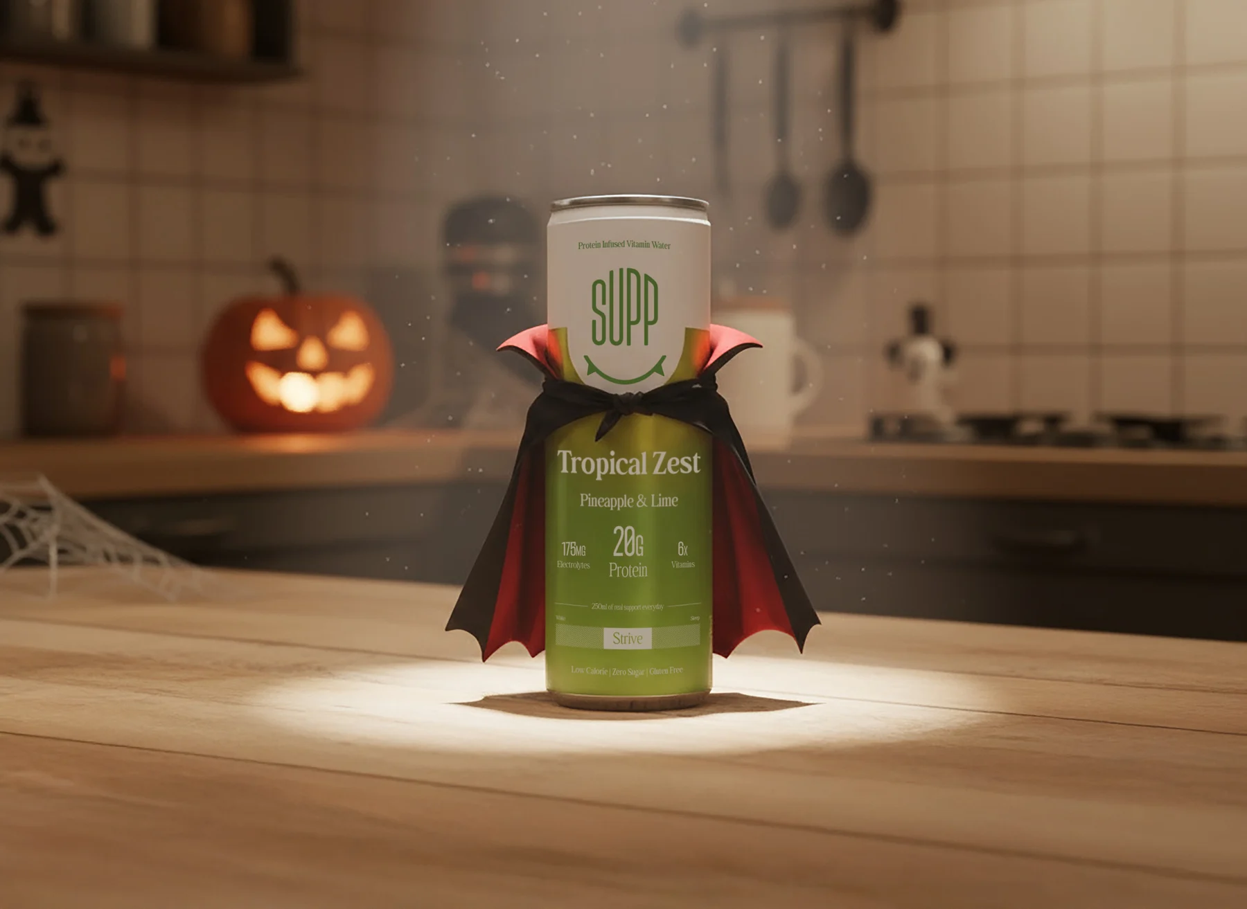 A Supp Tropical Zest can wearing a little vampire cape on a kitchen worktop with a carved pumpkin behind