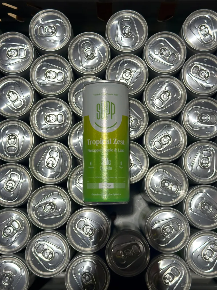 Supp Tropical Zest can lying on rows of sealed silver can tops, shot from above