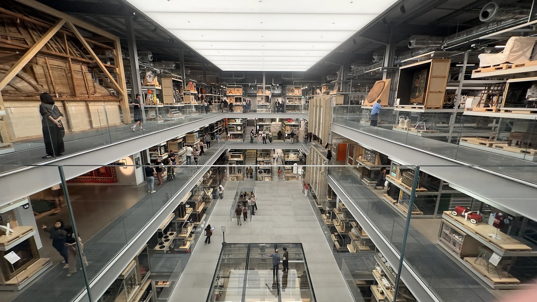 Looking down the length of a multi-level museum storehouse with shelves of objects and walkways